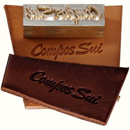 A brass stamp and embossed leather labels reading Compos Sui