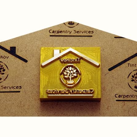 A brass stamp for a carpentry logo with its burned marks on wood