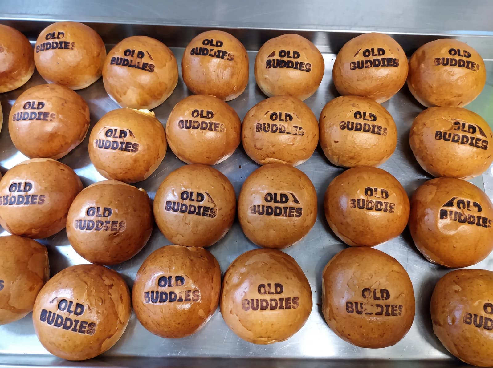 A bakery tray filled with buns each branded Old Buddies